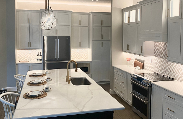 white cabinets with modern lighting pendants for island with stone countertops and wood flooring with custom tile backsplash